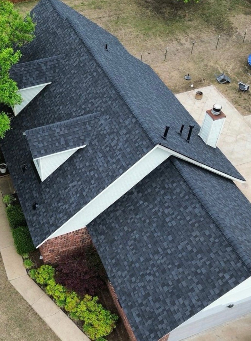 Drone view of a finished black shingle roof replacement by TTG Roof Pro's, ready for the winter season