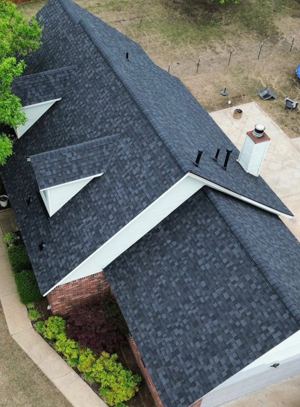 Aerial view of a completed black shingle roof on a brick home