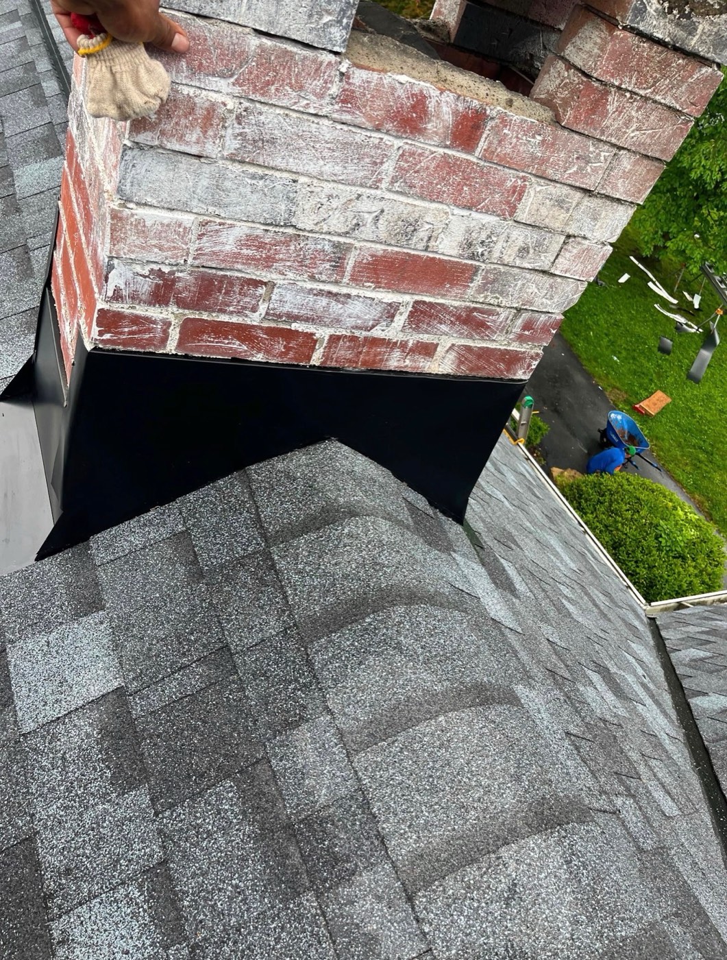 New black flashing sealed around a brick chimney
