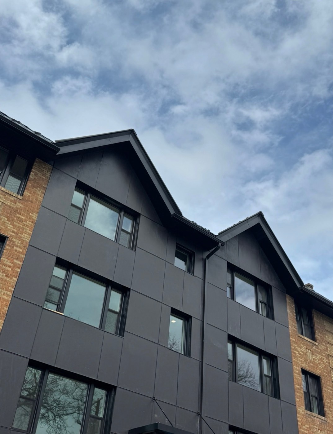 Apartment building with new dark vertical siding and brick exterior