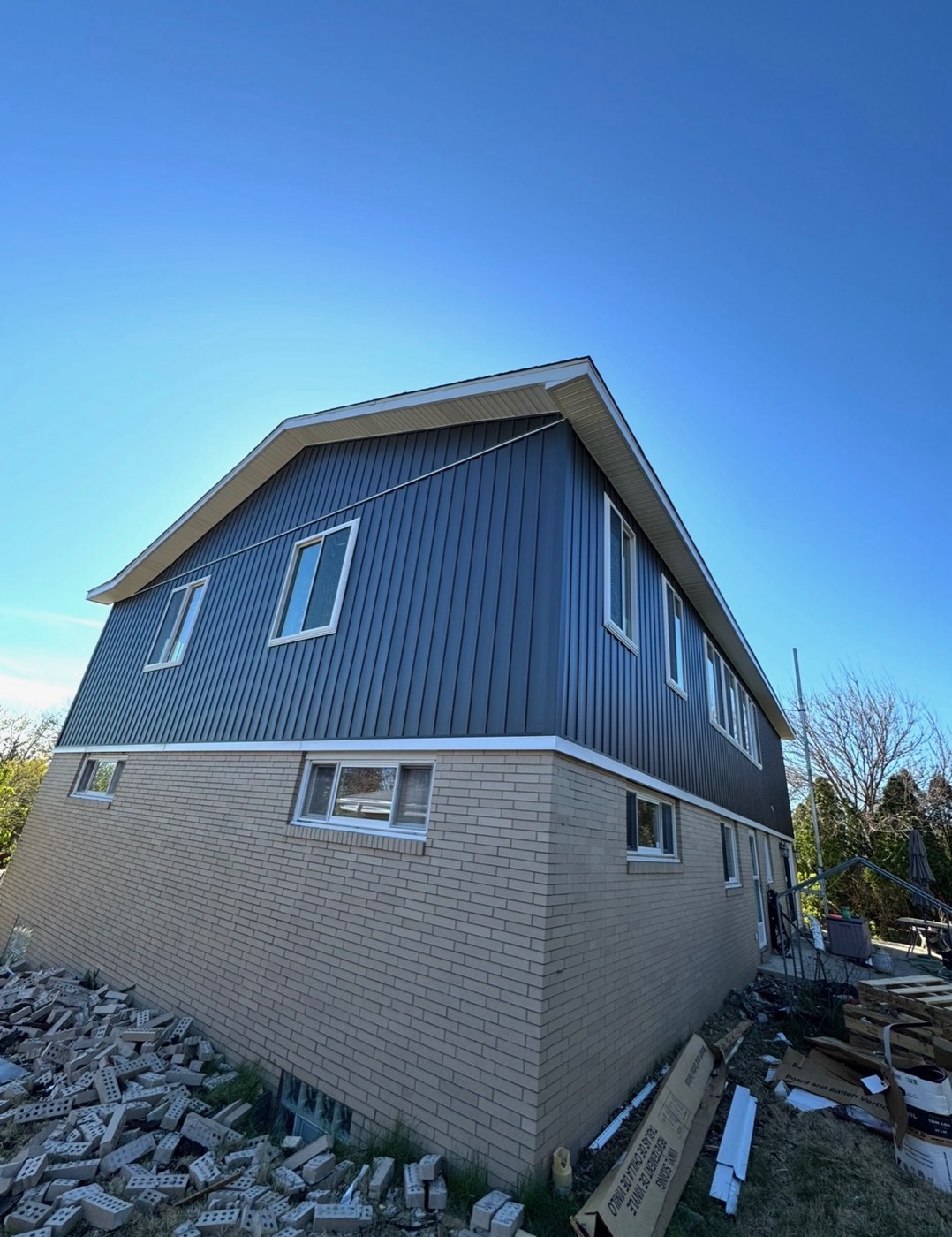 New-build home with slate-blue vertical siding over brick