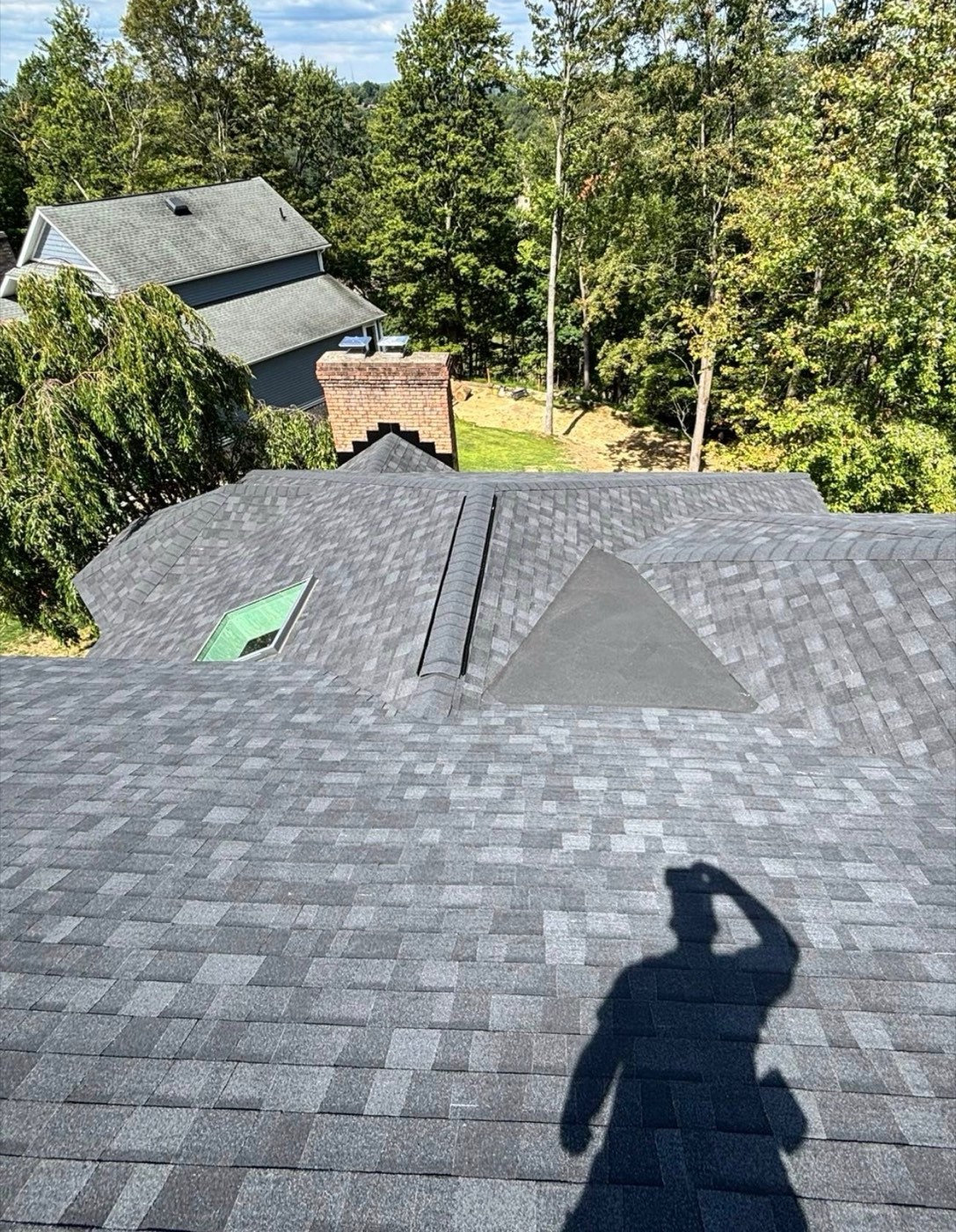 Ridge view of a new gray blend shingle roof with skylight